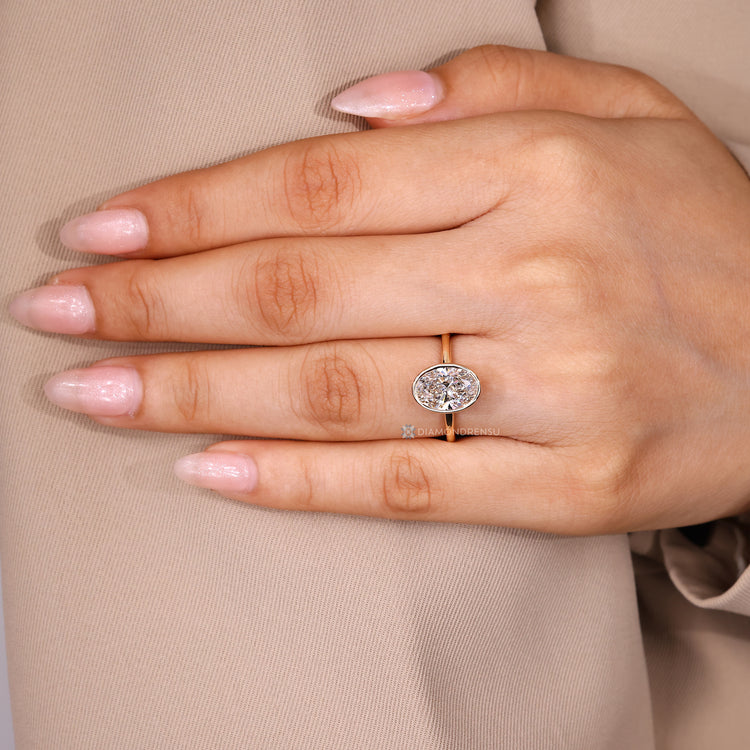 Oval diamond ring featuring a bezel set centre stone.