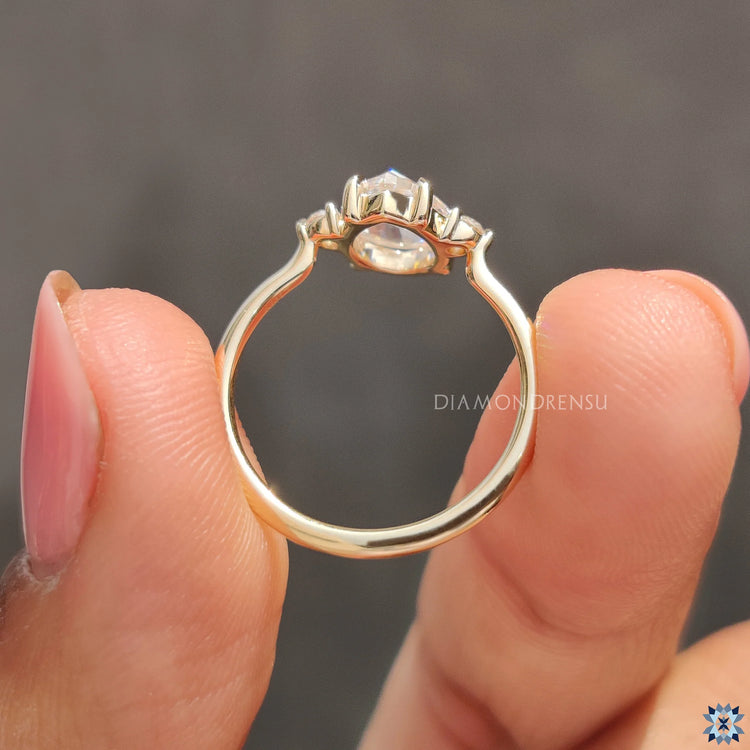 Unique Engagement Ring in yellow gold, featuring round side stones and a claw prong setting.