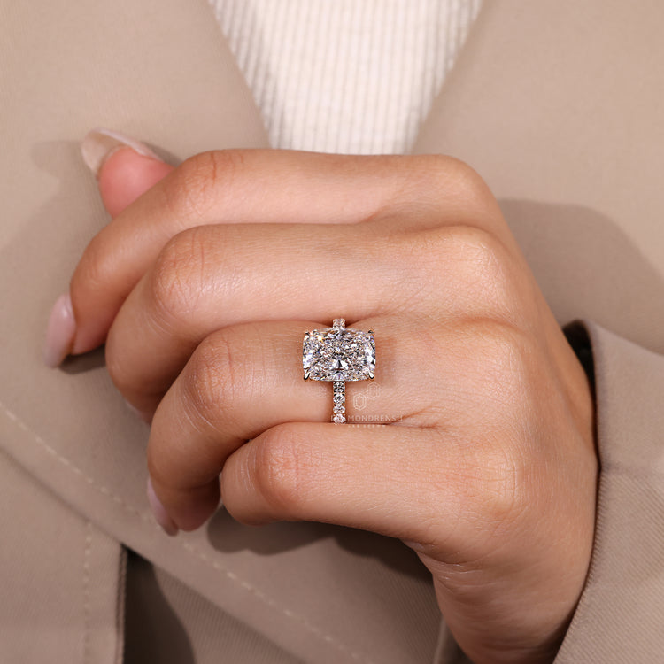 Elongated cushion ring with round diamond pave band.