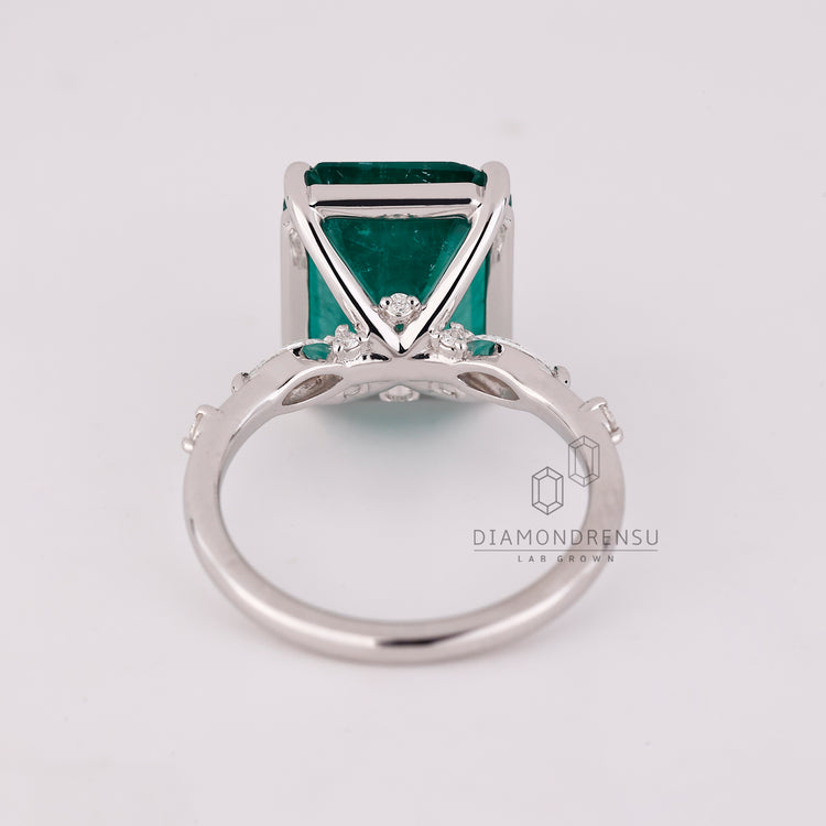 Emerald gemstone ring pave band prong setting style.