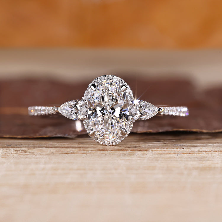 Oval cut diamond ring with pear cut side stones and round halo setting.