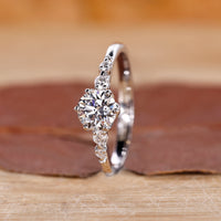 Round engagement ring with five diamonds in tapered shank design.