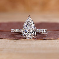 Pear shaped diamond ring with pave setting in white gold.
