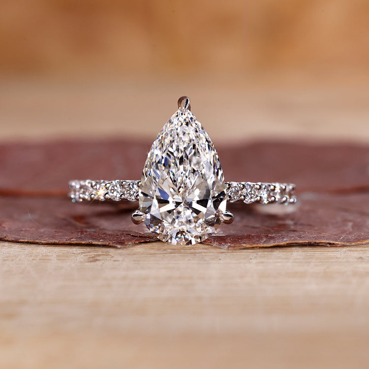 Pear shaped diamond ring with pave setting in white gold.