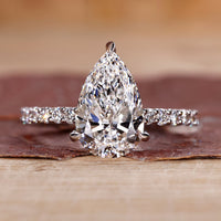 Pear shaped diamond ring with pave setting in white gold.