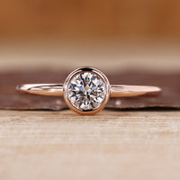 Solitaire diamond ring with round diamond in a smooth bezel setting.