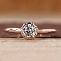 Solitaire diamond ring with round diamond in a smooth bezel setting.