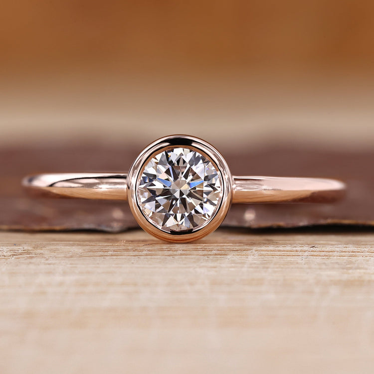 Solitaire diamond ring with round diamond in a smooth bezel setting.