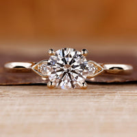 Round diamond ring in three stone style with pear shape outline.