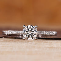 Round cut diamond ring pave tapered shank four prong.