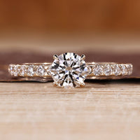 Round diamond ring with pave setting and four claw prong design.