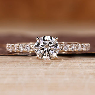 Round diamond ring with pave setting and four claw prong design.