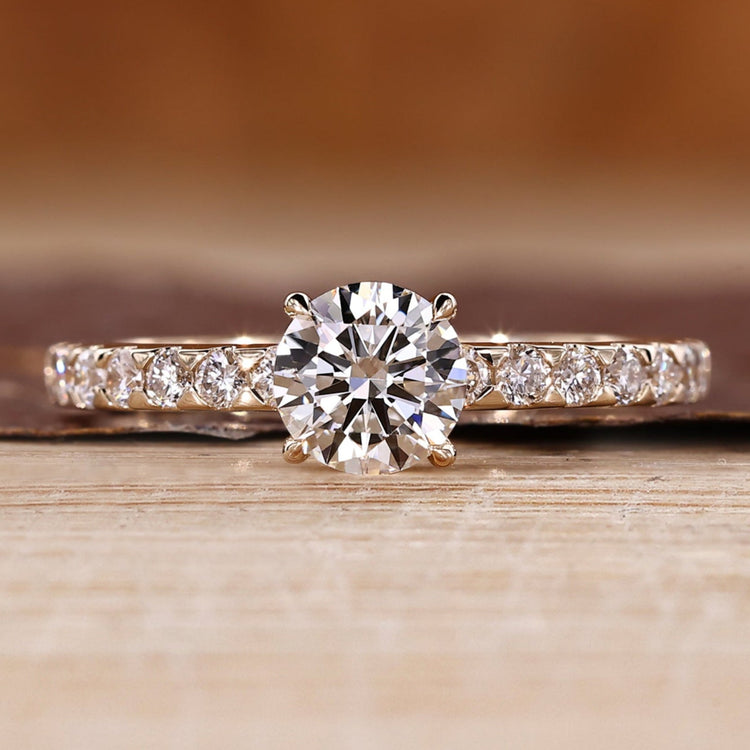 Round diamond ring with pave setting and four claw prong design.