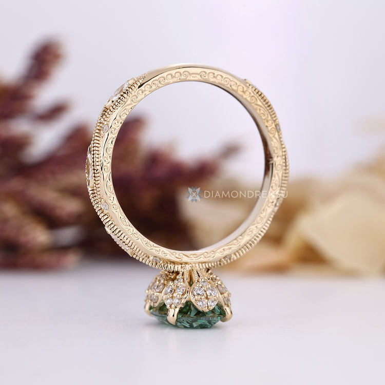 Oval diamond ring with green diamond and four claw prongs.