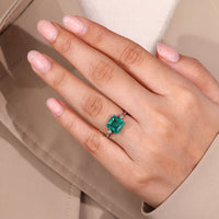 Emerald gemstone ring hidden halo prong setting style.