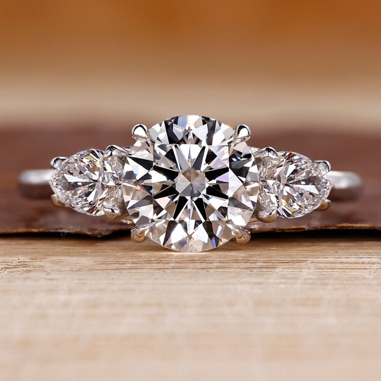 Round cut diamond ring pear side stones three stone.