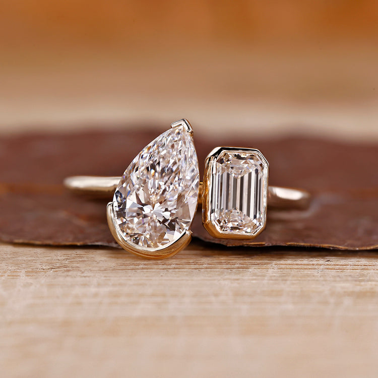 Toi et moi ring pear emerald diamond bezel prong set.