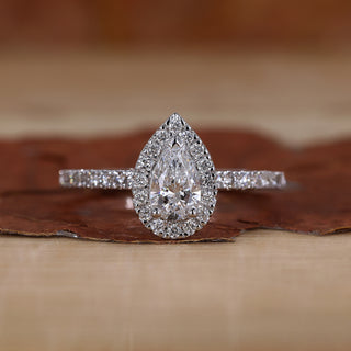 Pear halo engagement ring with round cut pave band.
