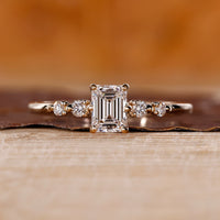 Emerald Cut Diamond Ring with round side stones and tapered shank.
