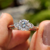 Round cut moissanite engagement ring with side stones.