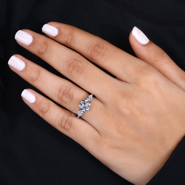 Pear side stone engagement ring featuring a central diamond and tapered side stones.
