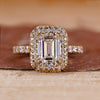 Emerald cut engagement ring with two side halo ring.
