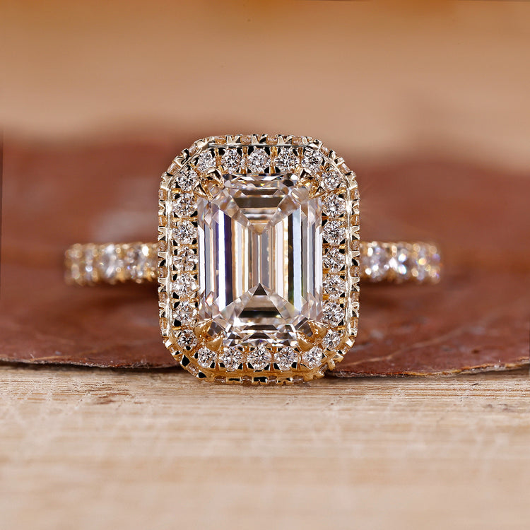 Emerald cut engagement ring with two side halo ring.
