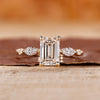 Emerald cut engagement ring with marquise and round side stone.
