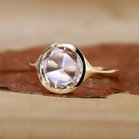 Bezel set engagement ring in yellow gold with a smooth finish.
