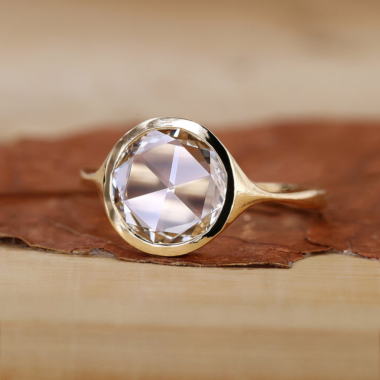 Bezel set engagement ring in yellow gold with a smooth finish.
