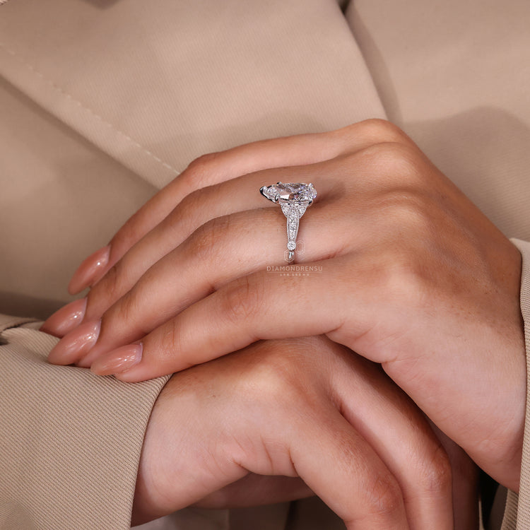 White gold ring with pear cut diamond and milgrain detail.
