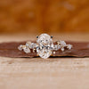 Side stone engagement ring with oval diamond and marquise accents in yellow gold.
