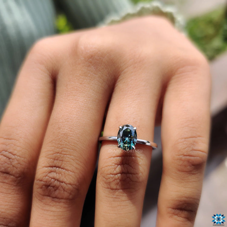 Unique engagement ring with a greenish blue stone in a white gold claw prong setting.