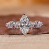 Marquise cut engagement ring with round side stones in white gold.
