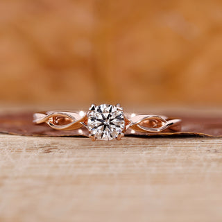 Solitaire diamond ring with round cut diamond and twisted shank in rose gold.
