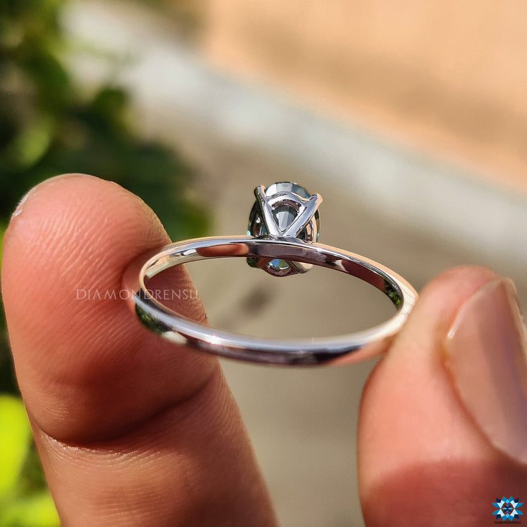 White gold ring featuring a greenish blue stone in an oval cut setting.