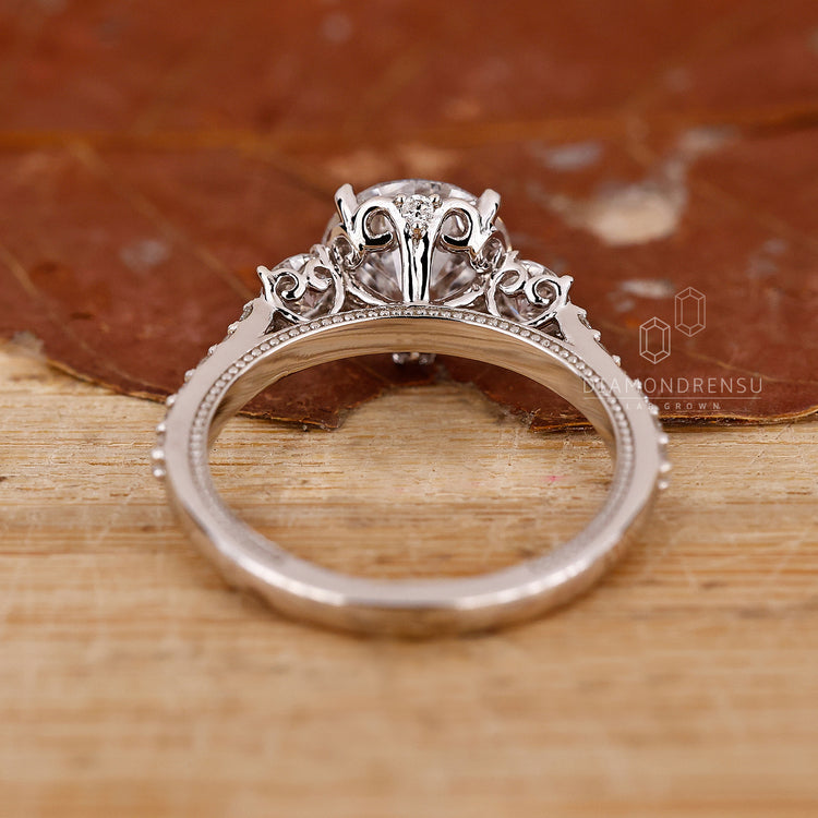 White gold ring with 3 stone round diamonds and milgrain finish.
