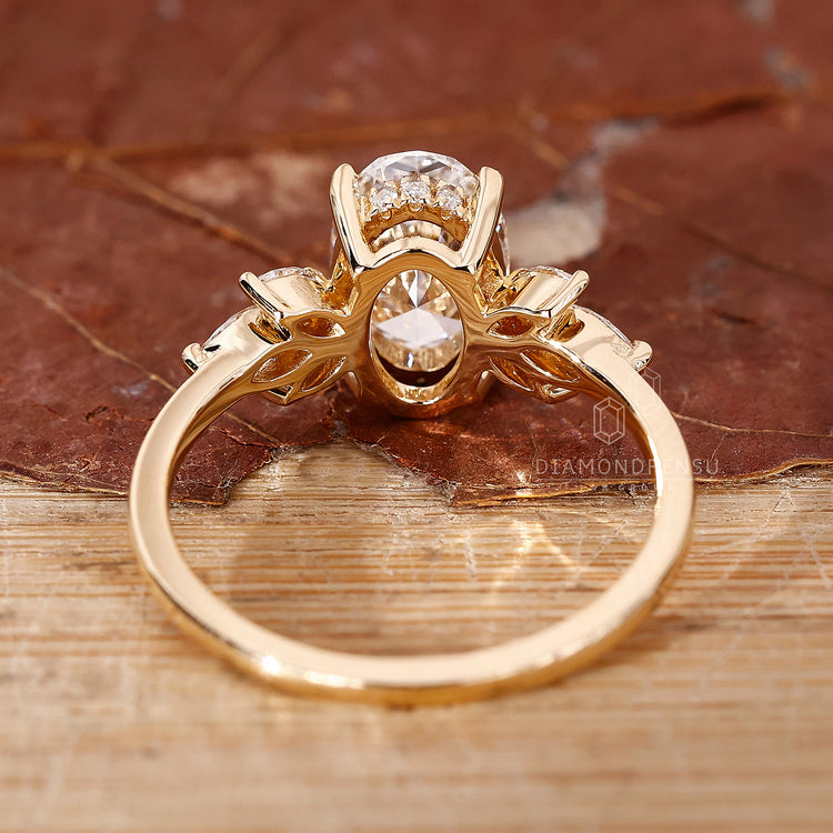 Claw prong setting yellow gold ring with oval cut diamond and halo design.
