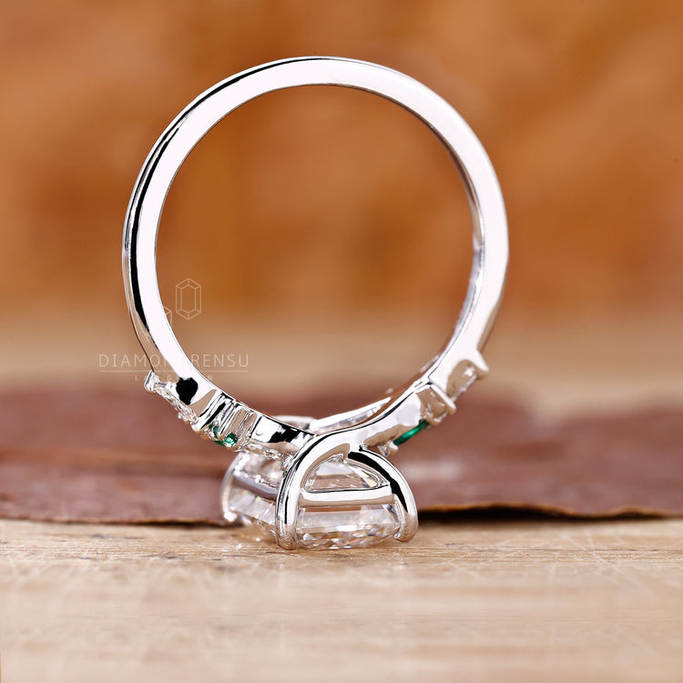Lab grown diamond ring with emerald centre and round side stones.
