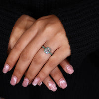 Claw prong setting white gold ring with radiant diamond and emerald halo detailing.
