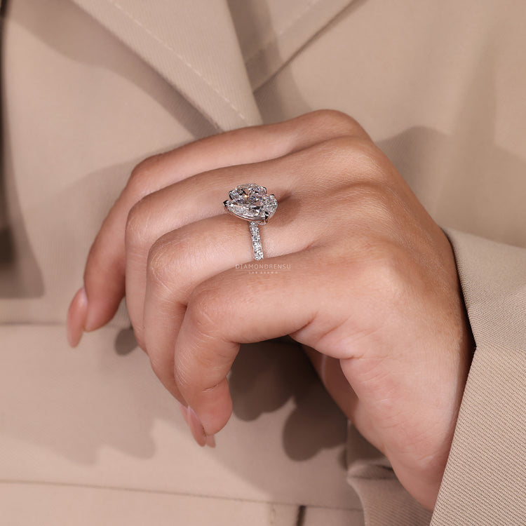 Claw prong setting ring featuring pear and round diamonds in white gold.

