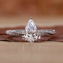 Close-up of a pear shaped diamond ring featuring twisted diamond pave