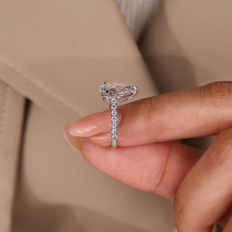 Elegant pear cut diamond ring with pave setting details.
