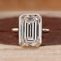 Bezel set emerald cut diamond ring with solitaire design.