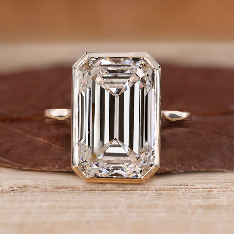 Bezel set emerald cut diamond ring with solitaire design.
