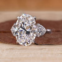 Three stone diamond ring with oval centre and trillion sides.