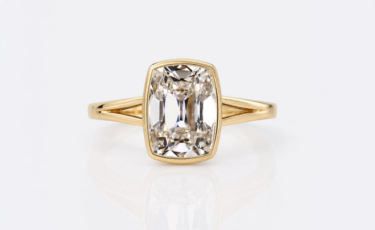 Bezel set cushion cut engagement ring with a smooth metal rim setting