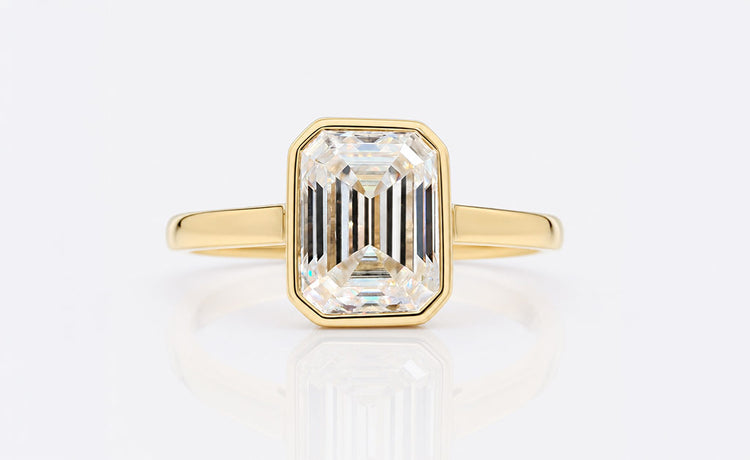 Emerald cut moissanite solitaire ring on a plain solid gold band