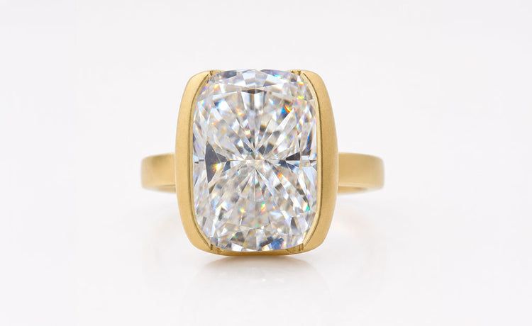 Moissanite solitaire engagement ring with a single brilliant cut stone on a plain gold band