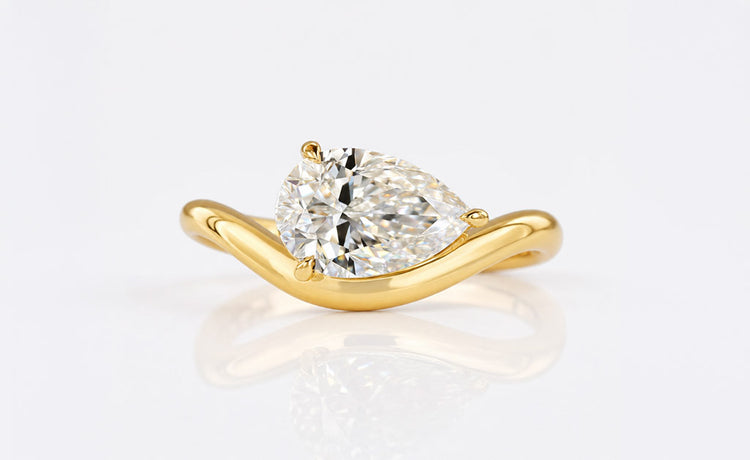 Pear cut moissanite solitaire ring on a plain solid gold band